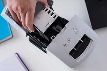 Woman loading a Brother continuous DK label roll into the Brother QL-600R label printer