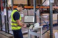 Man wearing hi-vis printing label on Brother TD-4410D desktop label printer in warehouse