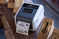 Brother TD-4550DNWB desktop label printer printing food label next to sandwiches