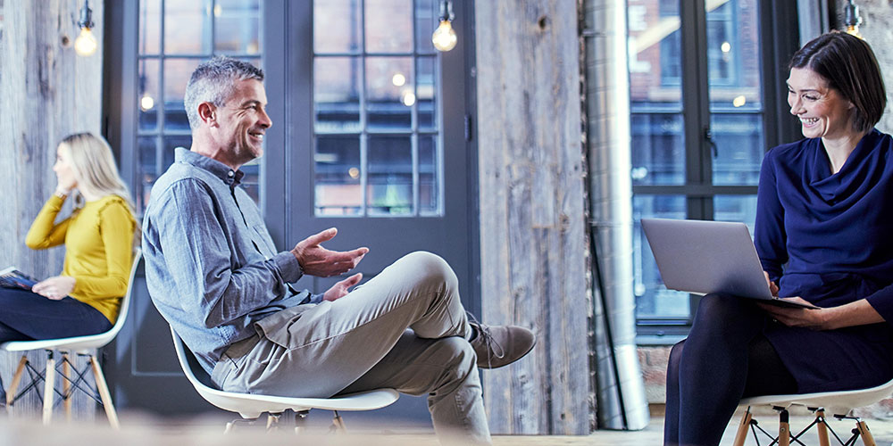 Business man laughing while sat at table with business woman
