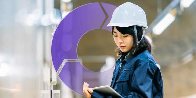 A woman wearing a hard hat, reading from a tablet device in a remanufacturing environment with a circular process graphic in the background