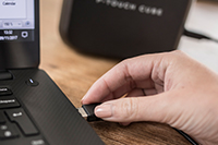 USB cable being plugged into a laptop computer to recharge the Brother label printer